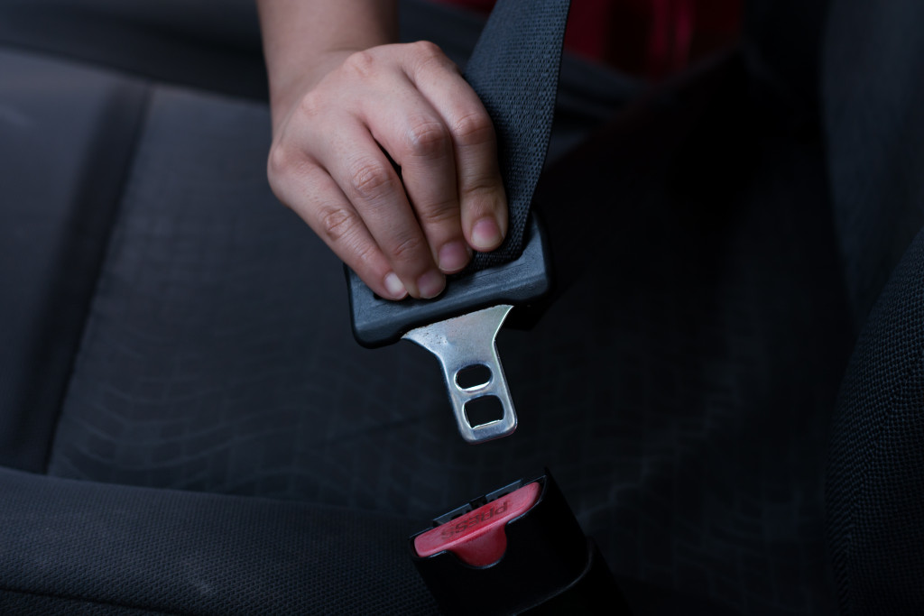 A hand clasping a seatbelt inside a car