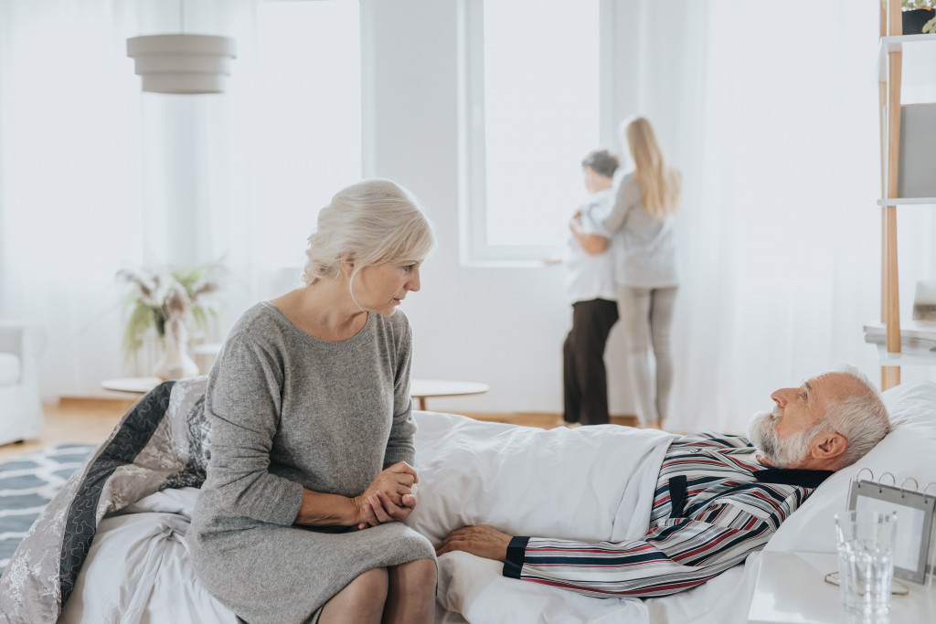 family with a sick man in bed in their home