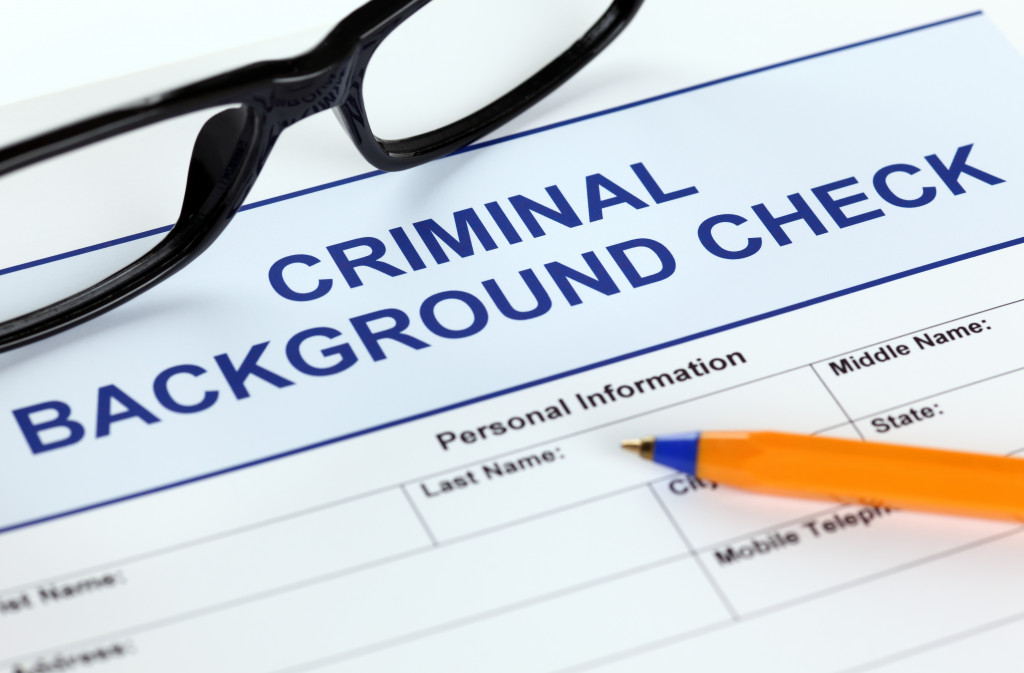 A criminal background check form, a pen, and eye glasses