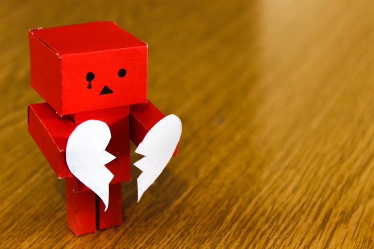 robot toy holding broken heart paper cutout