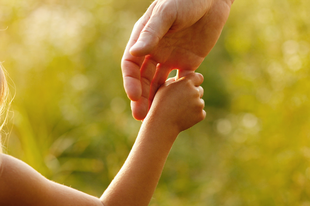 a parent holds the hand of a small child
