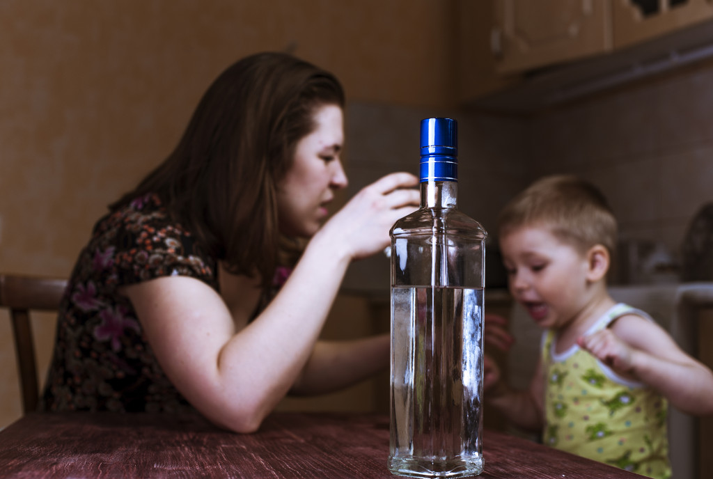 An alcoholic mother angry at her son while in the kitchen