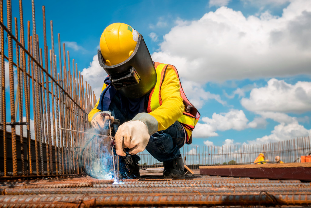 Construction worker wearing proper protective gear while welding at a construction site.