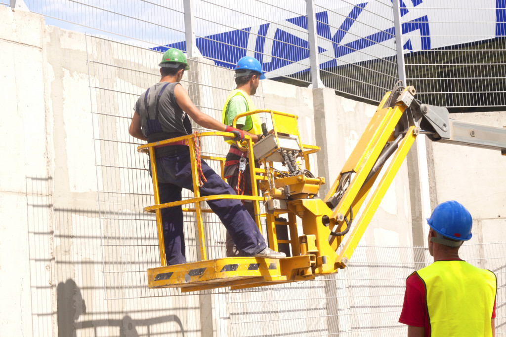 Hydraulic construction platform elevating two workers to a higher level at a construction site.