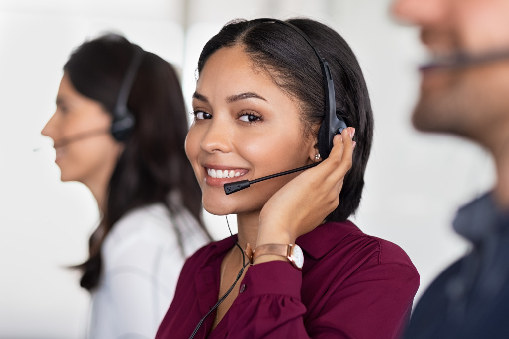 female customer service agent smiling while talking to person in headset