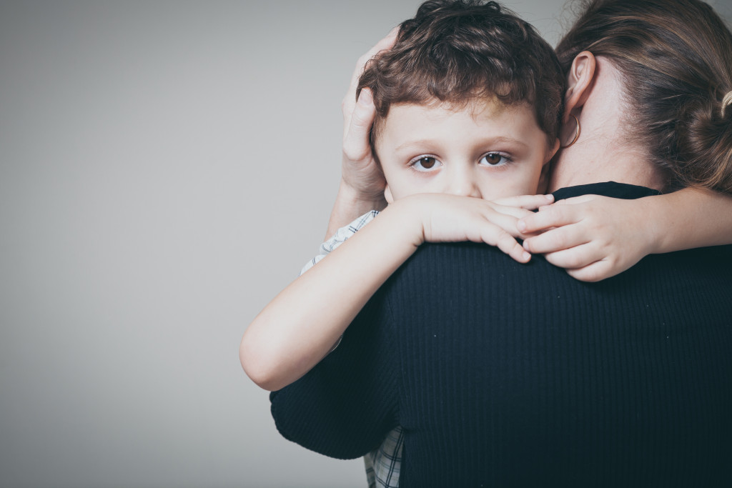 A mother hugging his sad son