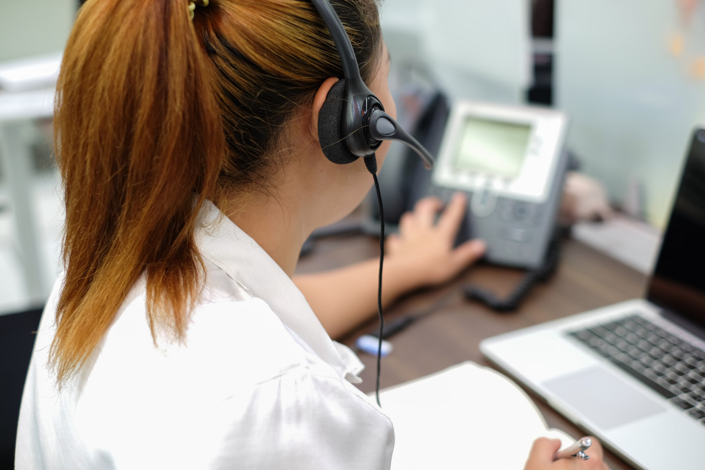 A woman talking to people on a phone with a headset at work